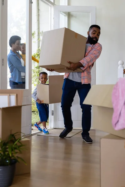 アフリカ系アメリカ人の両親と子供たちが新しい家の中に段ボール箱を運ぶ 変更されていない 子供時代 引っ越しの家と移転の概念 — ストック写真