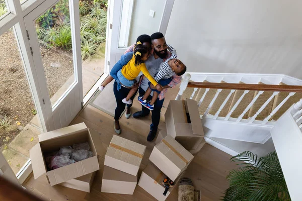 新しい家の中の箱のそばに立っている間 アフリカ系アメリカ人の家族の高い角度から見ることができます 変更されていない 子供時代 移動する家と移転の概念 — ストック写真