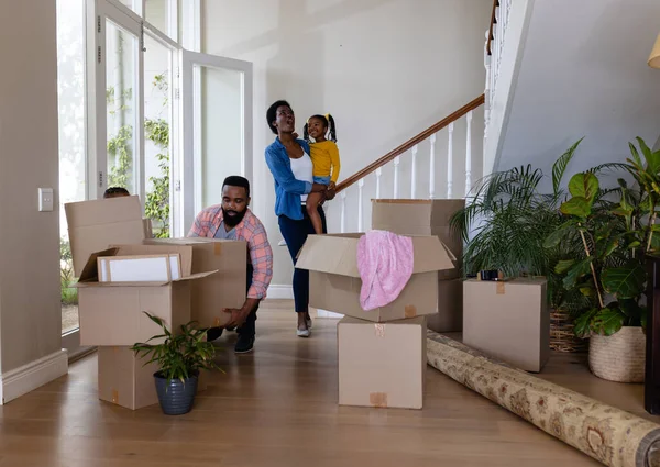 アフリカ系アメリカ人の両親と新しい家の床に段ボール箱を持つ子供たち 変更されていない 子供時代 引っ越しの家と移転の概念 — ストック写真