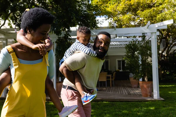 在阳光明媚的日子里 非裔美国人的父母背着儿女在后院散步 不变的生活方式 游戏和享受概念 — 图库照片