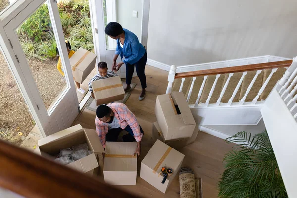 新しい家の中で段ボール箱を運ぶアフリカ系アメリカ人の両親と子供の高い角度のビュー 変更されていない 子供時代 引っ越しの家と移転の概念 — ストック写真