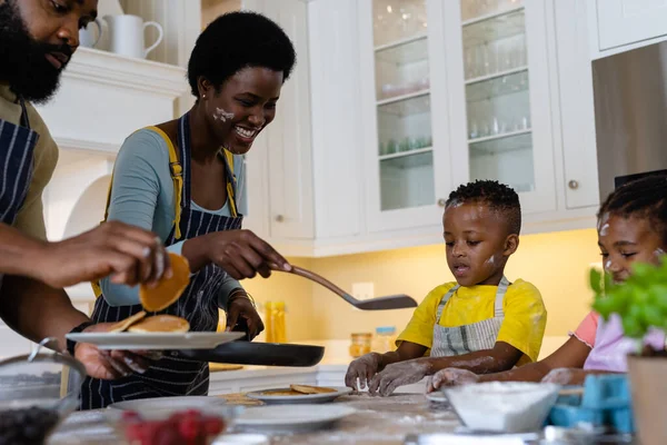 快乐的非洲裔美国父母在混乱的厨房岛上为儿子和女儿做煎饼 不变的生活方式 家的概念 — 图库照片