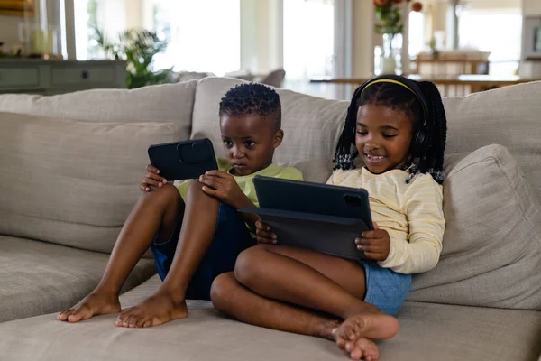Irmãos Afro Americanos Usando Tablet Digital Smartphone Enquanto Relaxam Sofá — Fotografia de Stock