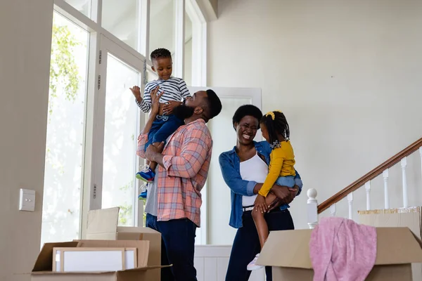 アフリカ系アメリカ人の明るい両親は新しい家に立っている間に子供を運ぶ 変更されていない 子供時代 引っ越しの家と移転の概念 — ストック写真