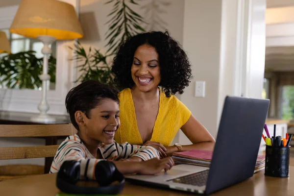 Gülümseyen Melez Anne Evde Dizüstü Bilgisayar Okuyarak Oğluna Bakıyor Değiştirilmemiş — Stok fotoğraf