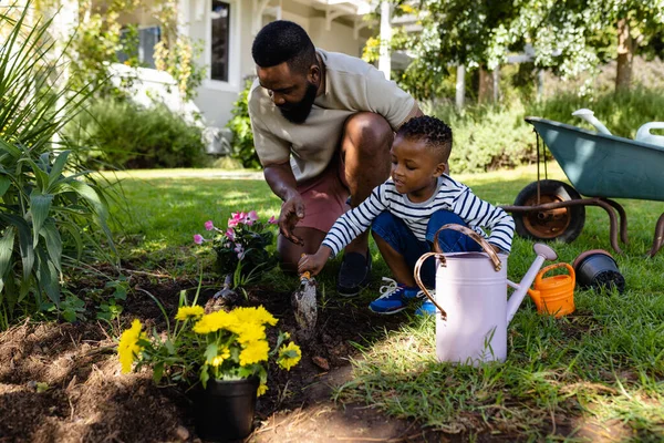 Padre Afroamericano Ayudando Hijo Cavar Tierra Para Plantar Flores Campo —  Fotos de Stock