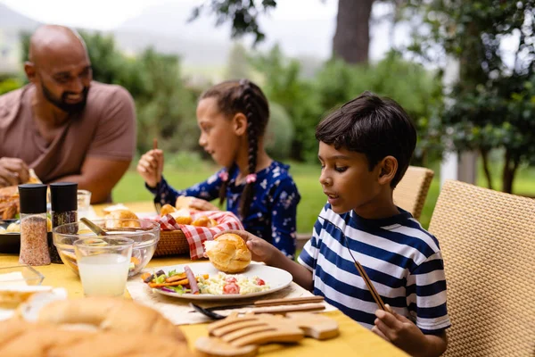 幸せな出産の父 息子と娘のテーブルで食事をし 庭で話して座っている 一緒に 食べ物とライフスタイル 変わらない — ストック写真