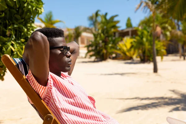 Relaxed Biracial Man Sunglasses Sitting Deckchair Sunny Beach Copy Space — Stock Photo, Image