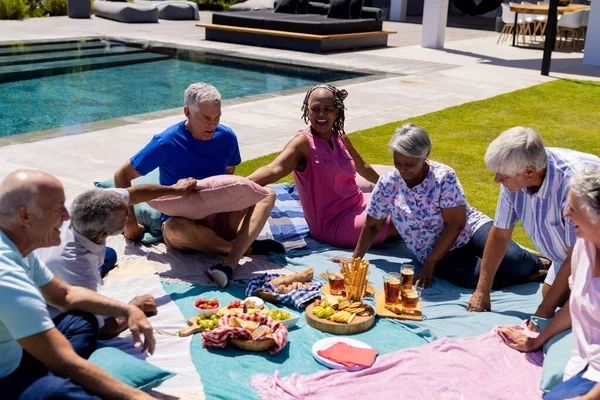 毛布の上に座って庭でピクニックをしている幸せな高齢者の多様な人々 シニアライフスタイル 友情とリラクゼーション 変わらない — ストック写真