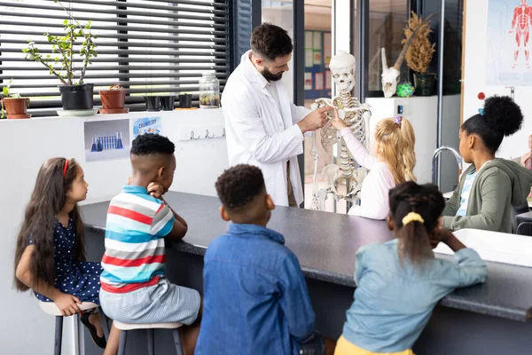 不同的男教师和小学生在生物课上学习骨骼 包容性 小学教育和学习概念 — 图库照片