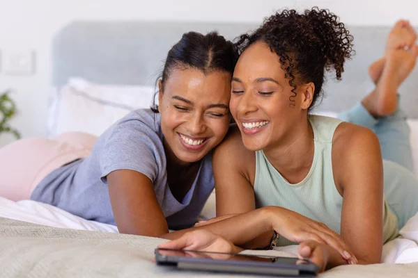Szczęśliwa Dwurasowa Para Lesbijek Obejmująca Korzystająca Tabletu Łóżku Sypialni Relaks — Zdjęcie stockowe