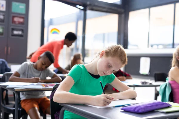 Gelukkig Kaukasisch Schoolmeisje Schrijven Aan Haar Bureau Met Diverse Leerlingen — Stockfoto