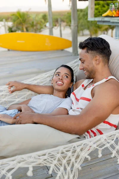 ビーチでハンモックでリラックスしながら お互いを見ている出産の若いカップルを笑顔 変更されていない 一緒に 観光リゾート 楽しみ ロマンスと夏のコンセプト — ストック写真