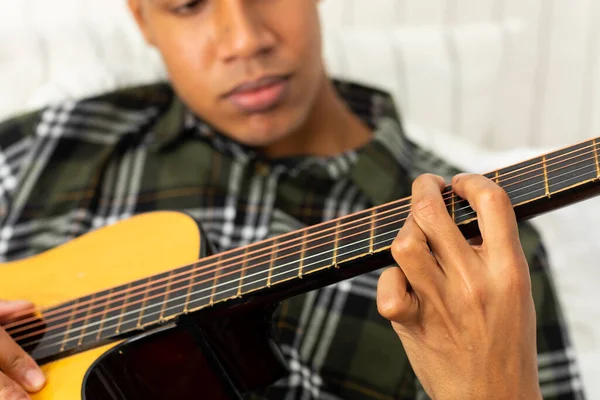 Primer Plano Del Hombre Biracial Sentado Cama Tocando Guitarra Casa —  Fotos de Stock