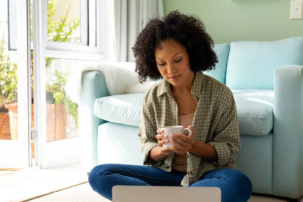 Biracial Woman Using Laptop Holding Cup Coffee Sitting Floor Bedroom — Stock Photo, Image