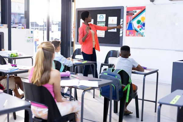 Diverse Pupils Sitting Desks Listening Female Teacher Pointing Whiteboard Copy — Stock Photo, Image