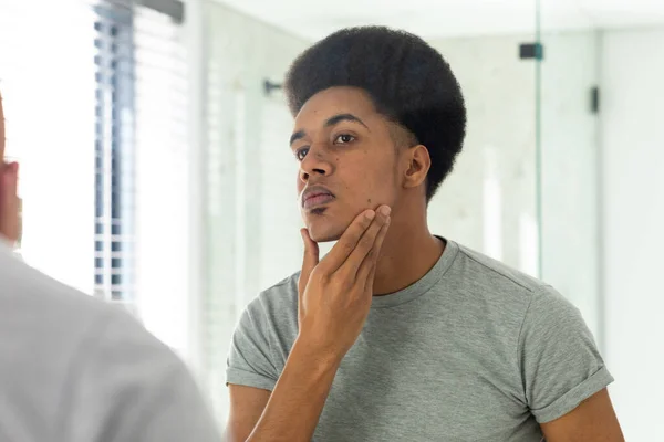 Biracial Man Tittar Spegeln Inspekterar Ansikte Och Hud Soligt Badrum — Stockfoto