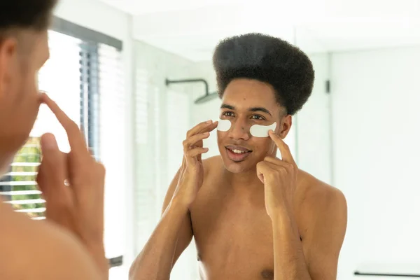 Glücklicher Mann Der Unter Augenmasken Sonnigen Badezimmer Den Spiegel Schaut — Stockfoto