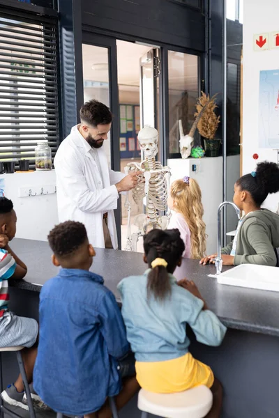 生物学の授業で骨格を研究する多様な男性教師と学童の垂直 スペースをコピーします コミュニティ 小学校 学習コンセプト — ストック写真