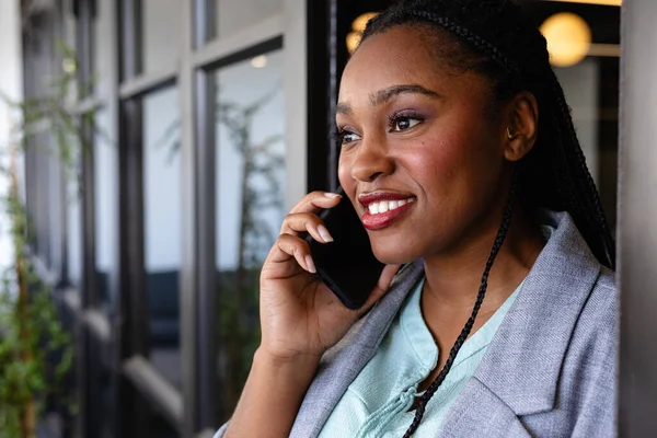 ハッピープラスサイズアフリカ系アメリカ人のカジュアルなビジネス女性がオフィスでスマートフォンで話しています カジュアルオフィス ビジネス 専門家 コミュニケーションと仕事 変更なし — ストック写真