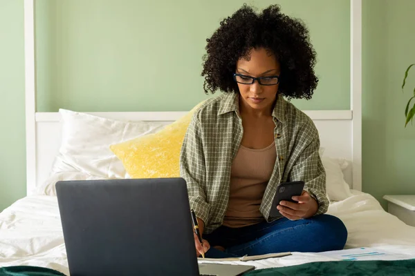Biracial Woman Doing Paperwork Using Laptop Smartphone Bed Bedroom Lifestyle — Stock Photo, Image