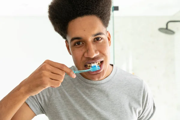 Homem Biracial Olhando Espelho Escovando Dentes Banheiro Ensolarado Autocuidado Atendimento — Fotografia de Stock