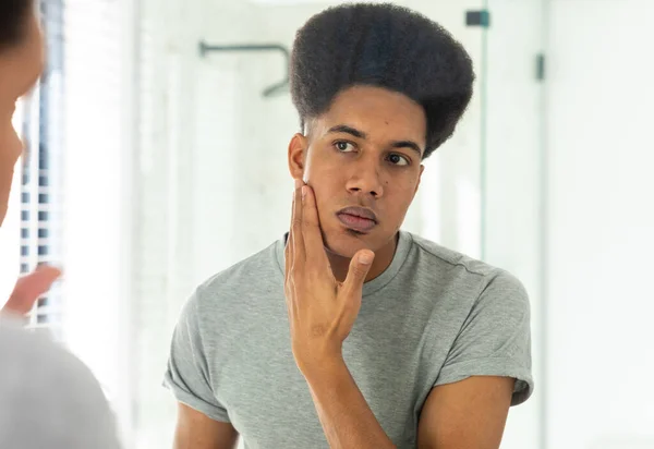 Biracial Man Tittar Spegeln Inspekterar Ansikte Och Hud Soligt Badrum — Stockfoto