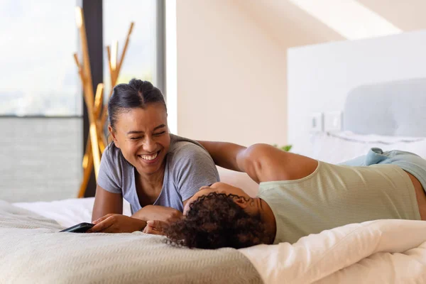 Feliz Pareja Lesbianas Birraciales Abrazando Utilizando Teléfono Inteligente Cama Dormitorio —  Fotos de Stock