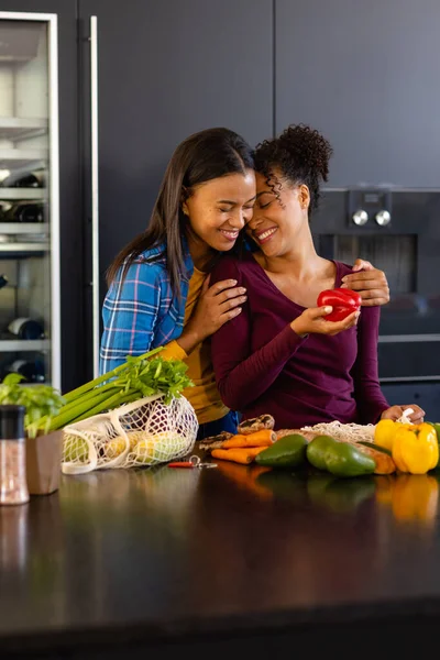 Happy Biracial Lesbian Couple Embracing Unpacking Groceries Kitchen Shopping Food — Stock Photo, Image