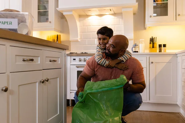 快乐的父亲和儿子拥抱和打包垃圾 在厨房里循环利用 生活方式 循环利用和家庭生活 — 图库照片