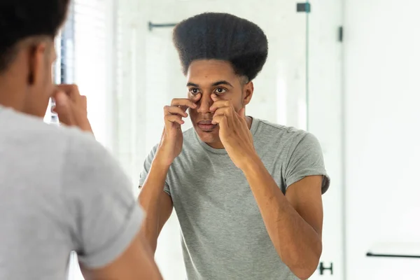 Hombre Biracial Mirando Espejo Inspeccionando Cara Los Ojos Baño Soleado — Foto de Stock