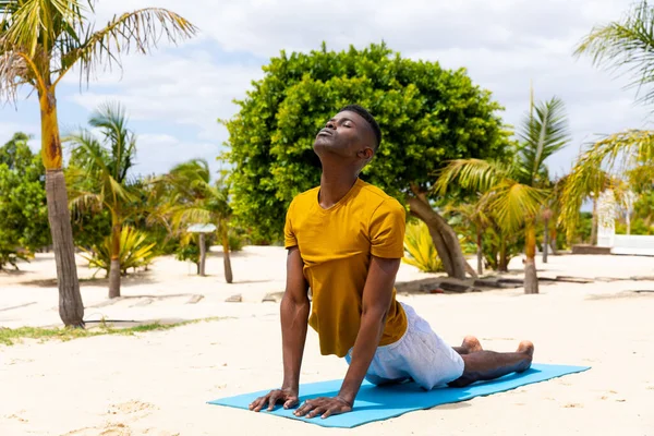 Skupiony Dwurasowy Mężczyzna Ćwiczący Jogę Rozciągający Się Macie Słonecznej Plaży — Zdjęcie stockowe