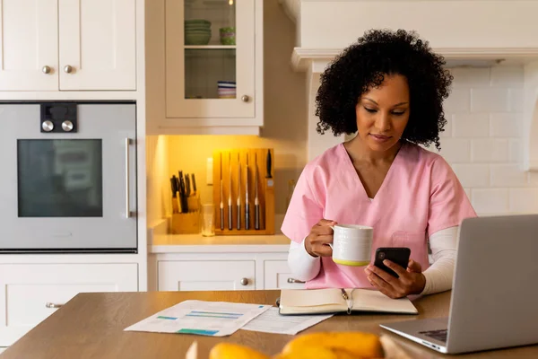 女性医务工作者使用智能手机和笔记本电脑 在厨房工作 复制空间 医疗服务 在家工作 远程工作 生活方式和家庭生活 — 图库照片
