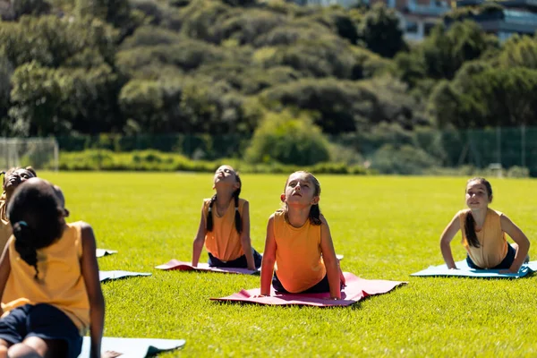 Diverse Studentesse Che Praticano Meditazione Yoga Sul Soleggiato Campo Sportivo — Foto Stock
