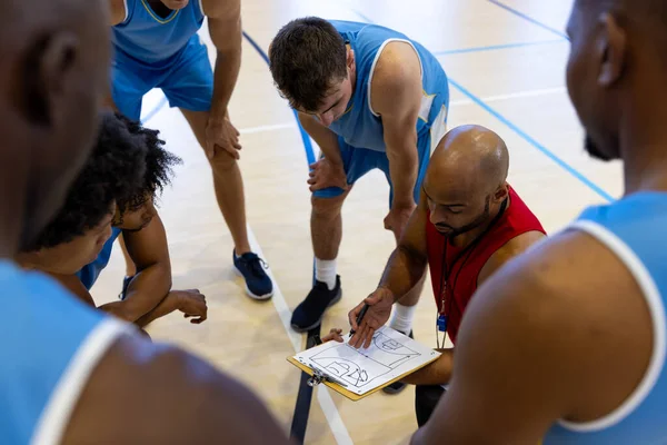 Çeşitli Erkek Basketbol Oyuncuları Antrenörle Spor Salonunda Oyun Planını Tartışıyor — Stok fotoğraf