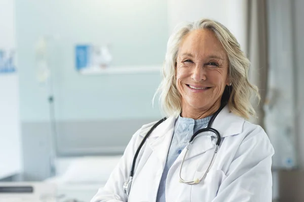 ハッピーシニアの白人女性医師の肖像画は 病院でラボコートとステスコープを着用しています 変わらない — ストック写真
