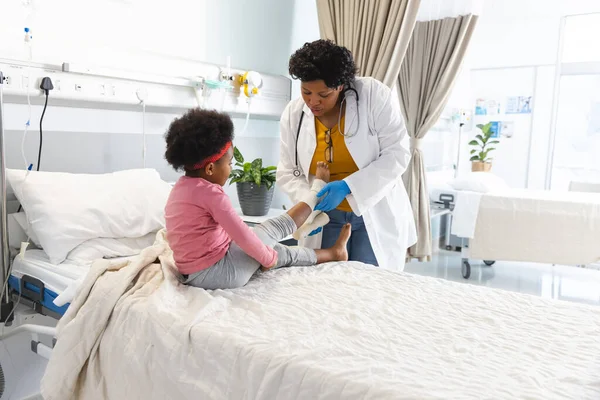 Afroamerykanka Lekarz Ubieranie Dziewczyny Nogi Pacjenta Bandażem Szpitalu Szpital Medycyna — Zdjęcie stockowe