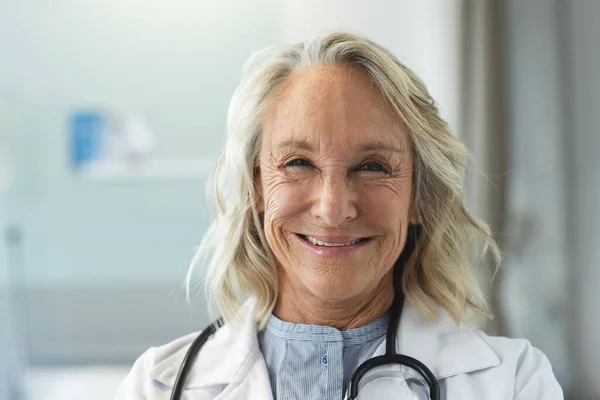 ハッピーシニアの白人女性医師の肖像画は 病院でラボコートとステスコープを着用しています 変わらない — ストック写真