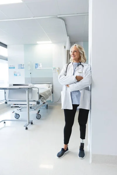 快乐的资深高加索女医生 穿着实验室外套 穿着人造腿在医院里 医疗和保健 未加改动 — 图库照片