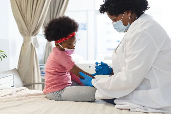 非洲裔美国女医生戴着口罩在医院为女病人接种疫苗 医药和保健 未经改动 — 图库照片