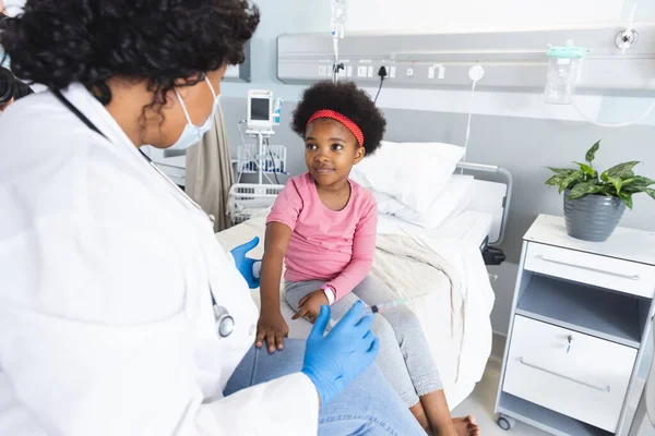 アフリカ系アメリカ人女性医師が病院で顔面マスクワクチン接種ガール患者を着用 医学および医療 変更されていない — ストック写真