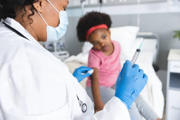 アフリカ系アメリカ人女性医師が病院で顔面マスクワクチン接種ガール患者を着用 医学および医療 変更されていない — ストック写真