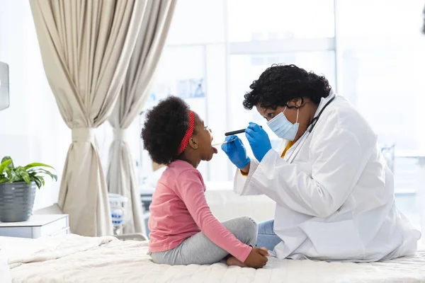 Afro Amerikaanse Vrouwelijke Arts Draagt Gezichtsmasker Onderzoeken Meisje Patiënt Het — Stockfoto