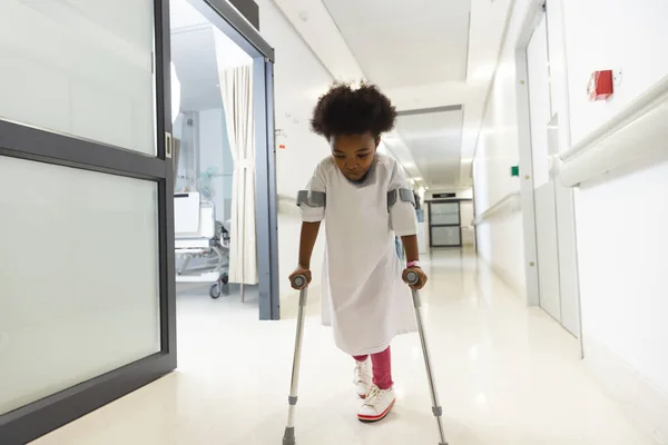 アフリカ系アメリカ人の少女患者が病院の廊下を歩いている 障害者 小児期 医学および医療 変わらない — ストック写真