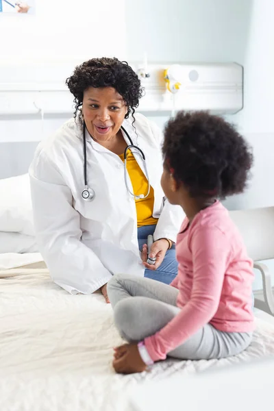 ハッピーアフリカ系アメリカ人女性医師が病院で少女患者と話している 変わらない — ストック写真
