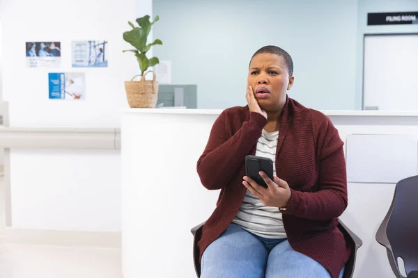 Huolestunut Afrikkalainen Amerikkalainen Naispotilas Joka Käyttää Älypuhelinta Odotushuoneessa Sairaalassa Kopioi — kuvapankkivalokuva