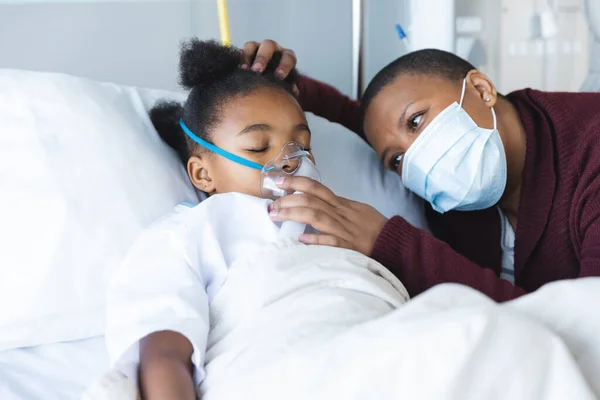 アフリカ系アメリカ人の少女患者は 病院で母親と共に酸素マスクでベッドに横たわっている 医学および医療 変わらない — ストック写真