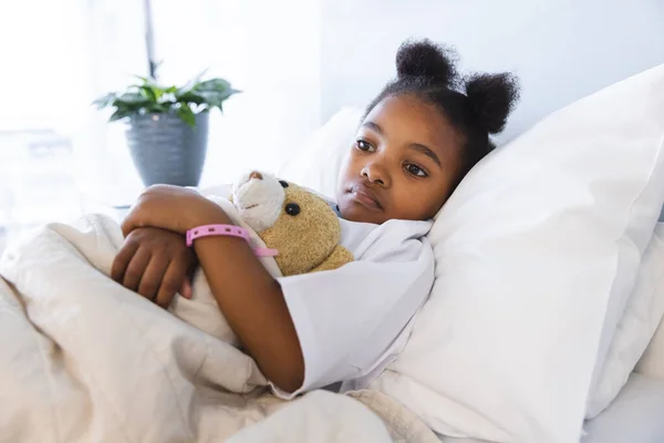 病院の患者室でテディベアとベッドに横たわっている悲しいアフリカ系アメリカ人少女 小児期 医学および医療 変更されていない — ストック写真