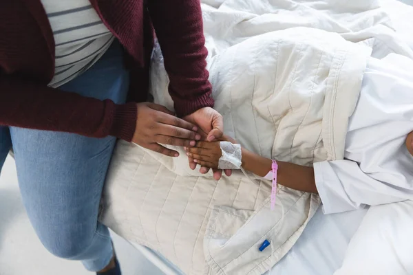 アフリカ系アメリカ人少女の患者がベッドに横たわり 病院で母親と手を握った — ストック写真