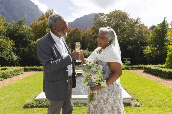 晴れた結婚式で庭でハッピーシニアの花嫁とグロムドリンクシャンパントースト ロマンス シニアライフスタイル 変わらない — ストック写真